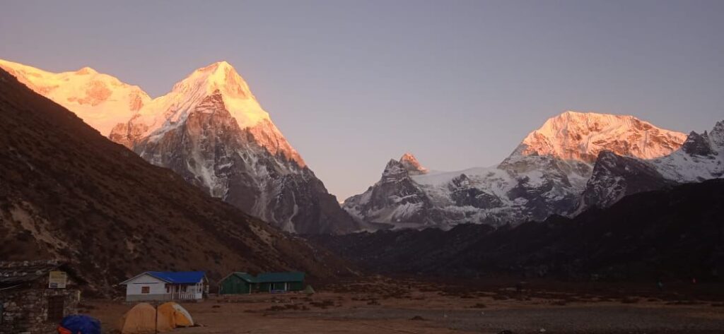 Sunrise view of snow-capped peaks and trekking tents at Kanchenjunga North Base Camp Trek in eastern Nepal