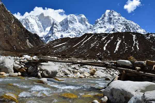 Scenic view of snowy Himalayan peaks and river crossing during Kanchenjunga North Base Camp trek in Nepal.