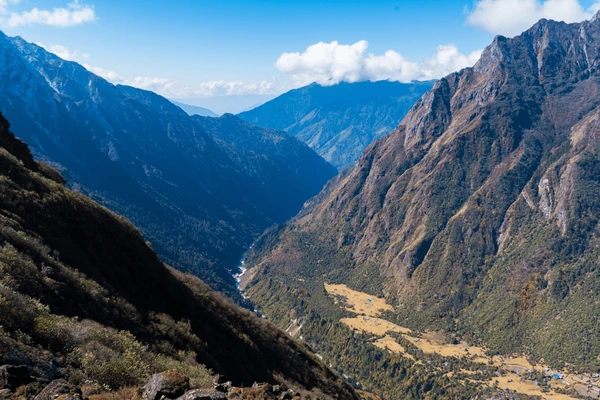 Scenic valley view with terraced fields and rugged mountains along the Kanchenjunga North Base Camp trek in Nepal.